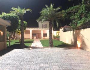 a house with palm trees in front of a driveway at StayApart - Aasmaa Farm Stay in Ābādpura