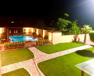 un patio trasero con piscina por la noche en StayApart - Aasmaa Farm Stay, en Ābādpura