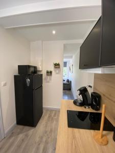 a kitchen with a black refrigerator in a room at L'Emile Zola in Saint-Quentin