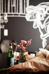 a table with a bottle and a vase of flowers at WDREI Hotel in Munich