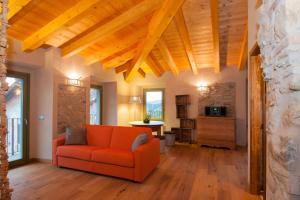 an orange couch in a living room with wooden ceilings at La Pentola dei Sogni in Scanzorosciate