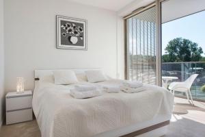 a white bedroom with a bed and a large window at Apartamenty Pinea in Pobierowo