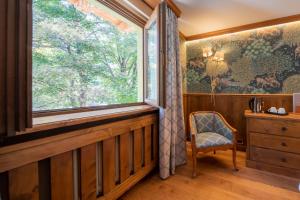 ein Fenster in einem Zimmer mit einem Stuhl und einer Kommode in der Unterkunft Gran Baita Hotel & Wellness in Courmayeur