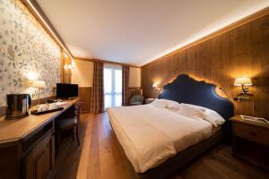 a hotel room with a large bed and a desk at Gran Baita Hotel & Wellness in Courmayeur