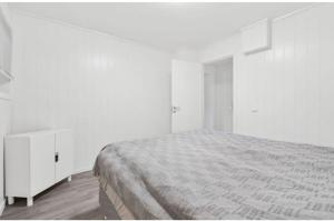 a white bedroom with a bed and white cabinets at Lovely 1 bedroom downstairs condo with free parking place in Svolvær