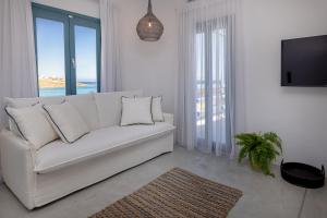 a white living room with a white couch and a tv at Royal-Ma Resort in Perástra