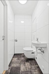 a white bathroom with a toilet and a sink at Lovely 1 bedroom downstairs condo with free parking place in Svolvær