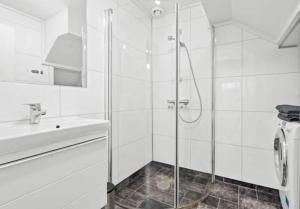 a white bathroom with a shower and a sink at Lovely 1 bedroom downstairs condo with free parking place in Svolvær
