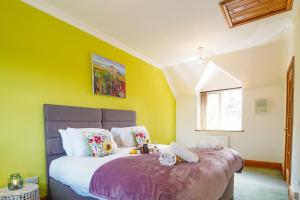 a bedroom with a large bed with yellow walls at Morea Cottage - 2 Bed in Horning