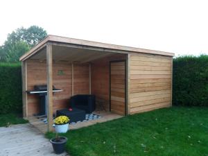 a wooden shed with a grill in a yard at Luxe bungalow op rustig vakantiepark. in Dronrijp