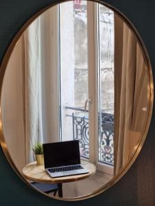 a mirror with a laptop sitting on a table in front of a window at Cosy studio in heart of Montmartre in Paris