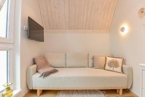 ein Wohnzimmer mit einem Sofa und einem TV in der Unterkunft Jaukus pajūrio namelis BOHO BEACH HOUSE su baseinu in Palanga