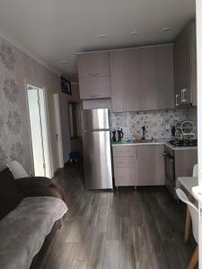 La cuisine est équipée de placards blancs et d'un réfrigérateur en acier inoxydable. dans l'établissement Batumi New Boulevard LINIMA, à Batoumi