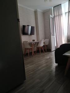 - un salon avec une table, des chaises et une télévision dans l'établissement Batumi New Boulevard LINIMA, à Batoumi