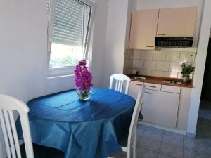 une table bleue avec un vase de fleurs violettes sur elle dans l'établissement Apartment Sun, à Klek
