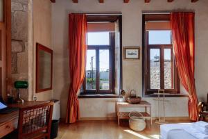 1 dormitorio con 2 ventanas con cortinas rojas en Venetico Palazzo en Khromonastírion