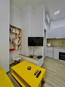 ein Wohnzimmer mit einem gelben Tisch und eine Küche in der Unterkunft Gersi's Daily Apartament in Tirana