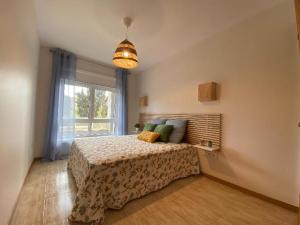 um quarto com uma cama e uma grande janela em Samil primera línea de playa em Vigo