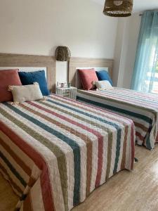 1 Schlafzimmer mit 2 Betten mit bunten Decken und Kissen in der Unterkunft Samil primera línea de playa in Vigo