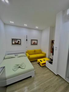 una camera con un letto e un divano giallo di Gersi's Daily Apartament a Tirana