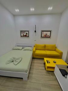 una camera con un letto e un divano giallo di Gersi's Daily Apartament a Tirana