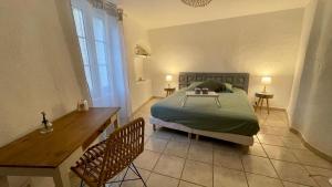 a bedroom with a bed and a table and two chairs at La Belle Histoire in Bize-Minervois