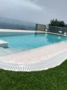 a large swimming pool with blue water and grass at Casa Nine con piscina in Breña Baja