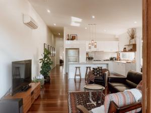 a living room with a couch and a kitchen at Byron Butter Factory Apartments in Byron Bay