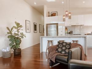 a living room with a couch and a kitchen at Byron Butter Factory Apartments in Byron Bay