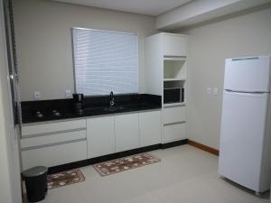 a kitchen with a white refrigerator and a window at Casa de Praia em Torres RS Praia Lagoa jardim in Torres
