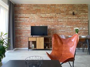 a living room with a brick wall and a television at Concordia apartment in Spišská Nová Ves