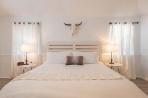 1 cama blanca con 2 lámparas y cabeza de cabra en la pared en Timeless-Texas-Inn - Heated Pool Oasis & Lux Vibe, en Round Rock