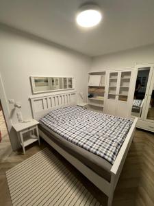 a white bedroom with a bed and a night stand at Balticus Apartament 2 pokoje, 5-piętro, klimatyzacja, widok na morze, duży balkon, garaż, internet in Międzyzdroje