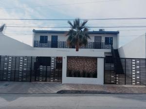a white house with a palm tree in front of it at Consulado Americano a 5 minutos D3 in Ciudad Juárez