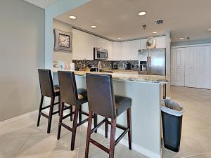 a kitchen with a bar with four chairs in it at Emerald Isle #1606 in Pensacola Beach