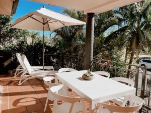 a patio with a white table and chairs and an umbrella at Sea Breeze on Main Beach in Byron Bay