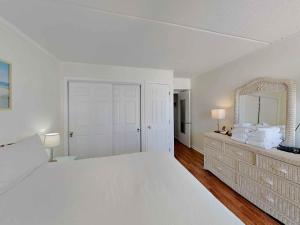 a white bedroom with a large bed and a mirror at Villas Capri #9 in Fort Walton Beach