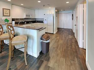 una cocina con armarios blancos, encimera y sillas en Emerald Isle #1506, en Pensacola Beach