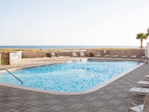 a swimming pool with chairs and the ocean in the background at Navarre Towers #203 in Navarre