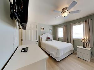 a bedroom with a tv and a bed with a white bedspread at Dory #E in Perdido Key