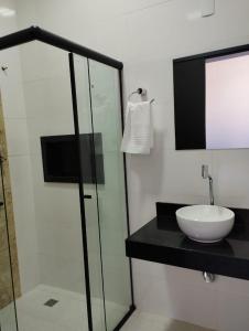 uma casa de banho com um lavatório e uma cabina de duche em vidro. em Canastra Flat Hospedagem em Vargem Bonita