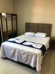 Una cama grande con sábanas blancas y toallas. en Canastra Flat Hospedagem, en Vargem Bonita