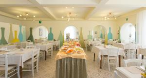 ein Restaurant mit weißen Tischen und Stühlen und bunten Vasen in der Unterkunft Hotel Trieste in Cesenatico