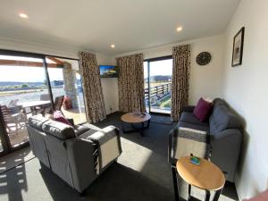 a living room with couches and chairs and a balcony at Uninterrupted Mountain Views in Twizel