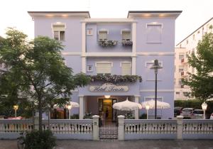 ein Gebäude mit einem weißen Zaun davor in der Unterkunft Hotel Trieste in Cesenatico