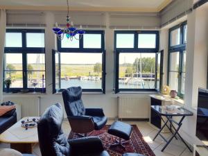 ein Wohnzimmer mit Stühlen, einem Tisch und Fenstern in der Unterkunft Ferienwohnung Yachthafenidyll - direkte Wasserlage am Hafen in Ostseebad Karlshagen