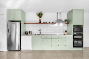una cucina con armadi verdi e frigorifero in acciaio inossidabile di The Dairy Sojourn Kangaroo Valley a Kangaroo Valley
