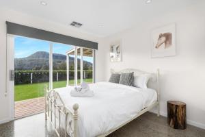 una camera con un letto bianco e una grande finestra di The Dairy Sojourn Kangaroo Valley a Kangaroo Valley