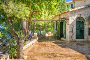 einen Backsteinsteg vor einem Haus mit einem Baum in der Unterkunft Nobelos Seaside Lodge in Agios Nikolaos