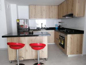 una cocina con dos taburetes rojos en un mostrador en Hermoso apartamento familiar con parqueadero privado, en San Gil